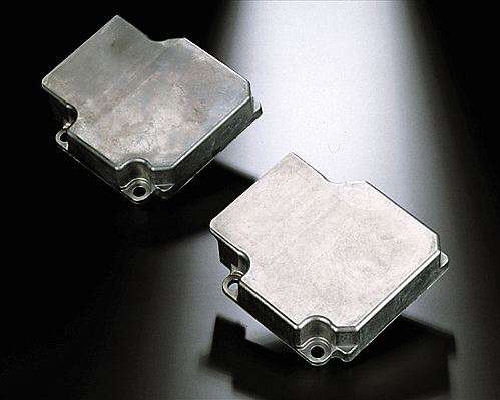 The image shows a pair of silver metal parts, known as brake pads, on a black surface. The parts are made of metal and have a glossy finish. They are arranged in a symmetrical pattern, with each part 