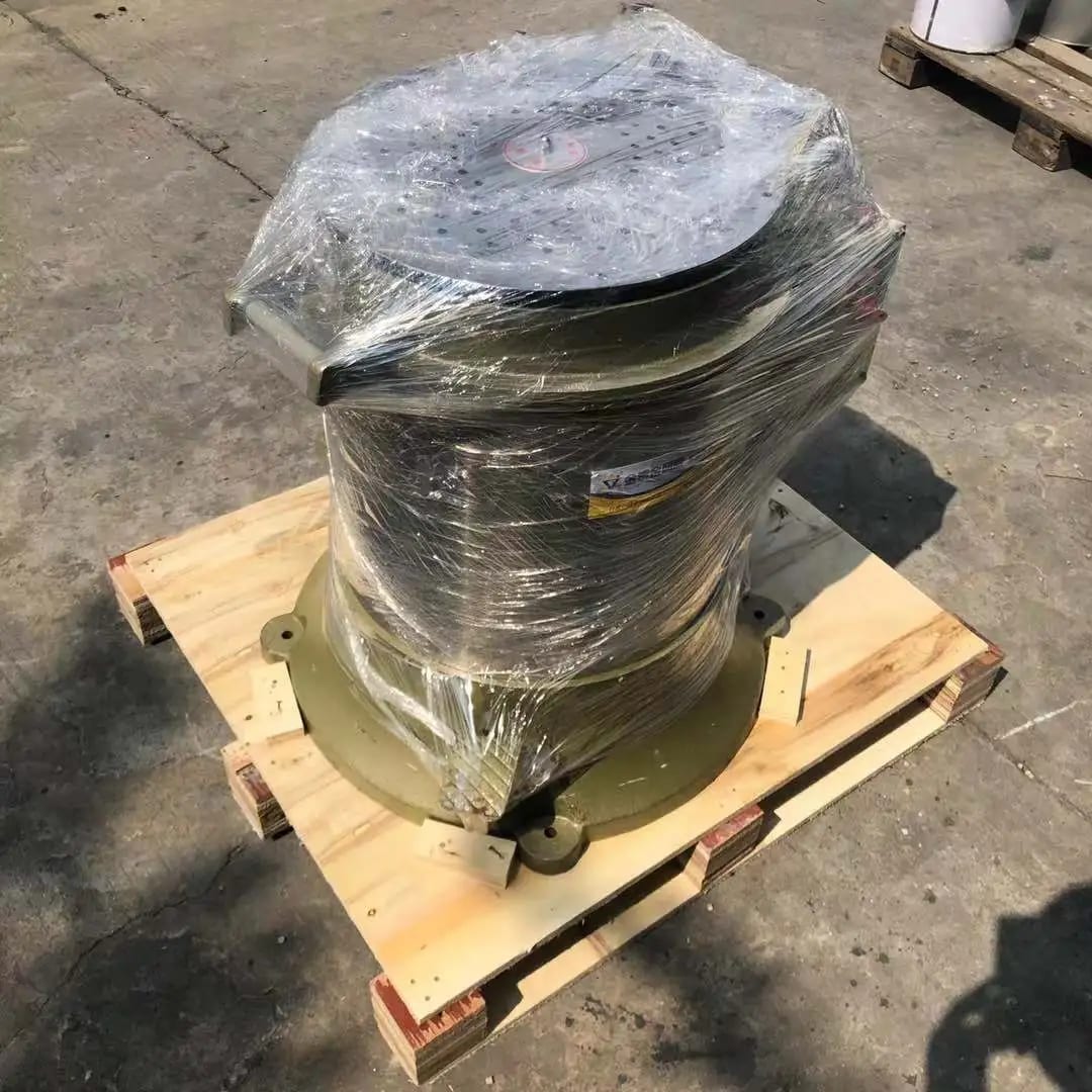 The image shows a wooden pallet with a large metal object on top of it, covered with a plastic cover. On the right side of the pallet, there are a few other objects, and the shadow of a person can be 